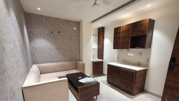 A modern living room with a beige sofa, a glass coffee table, and wooden cabinets. - IP Hill Nest By Qotel Sahastradhara (Dehradun)