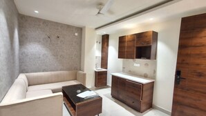 A modern living room with a sofa, coffee table, and wooden cabinets. - IP Hill Nest By Qotel Sahastradhara (Dehradun)