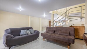 Sala de estar com dois sofás, escada e área de refeições.