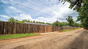 Un camino de tierra que lleva a una valla de madera con un edificio pequeño.