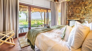 Un dormitorio con una cama grande, una pared de piedra y vistas al exterior.