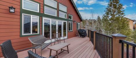 A wooden deck with outdoor furniture, a barbecue grill, and a view of a mountain.