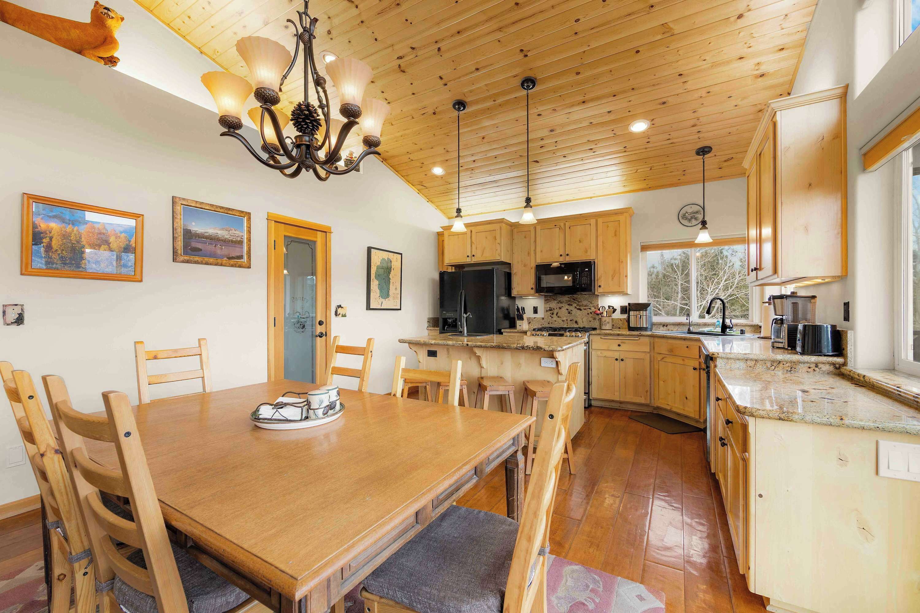 Una cocina amplia con armarios de madera, una mesa de comedor y una araña.