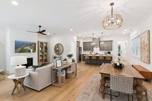 A spacious living room with a fireplace, a dining area with a wooden table and chairs, and a kitchen with modern appliances. - Liv'n the Good Life sleeps 11 (St Simons Island)