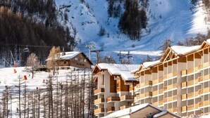 Estació d'esquí amb edificis de fusta, un remuntacamp i vessants nevades.