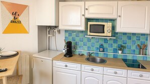 Een keuken met witte kastjes, een magnetron, een spoelbak en een koffiezetapparaat.