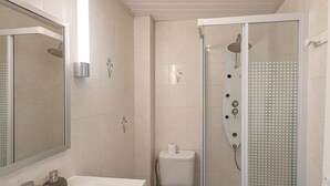 Een moderne badkamer met douche, toilet en wastafel.