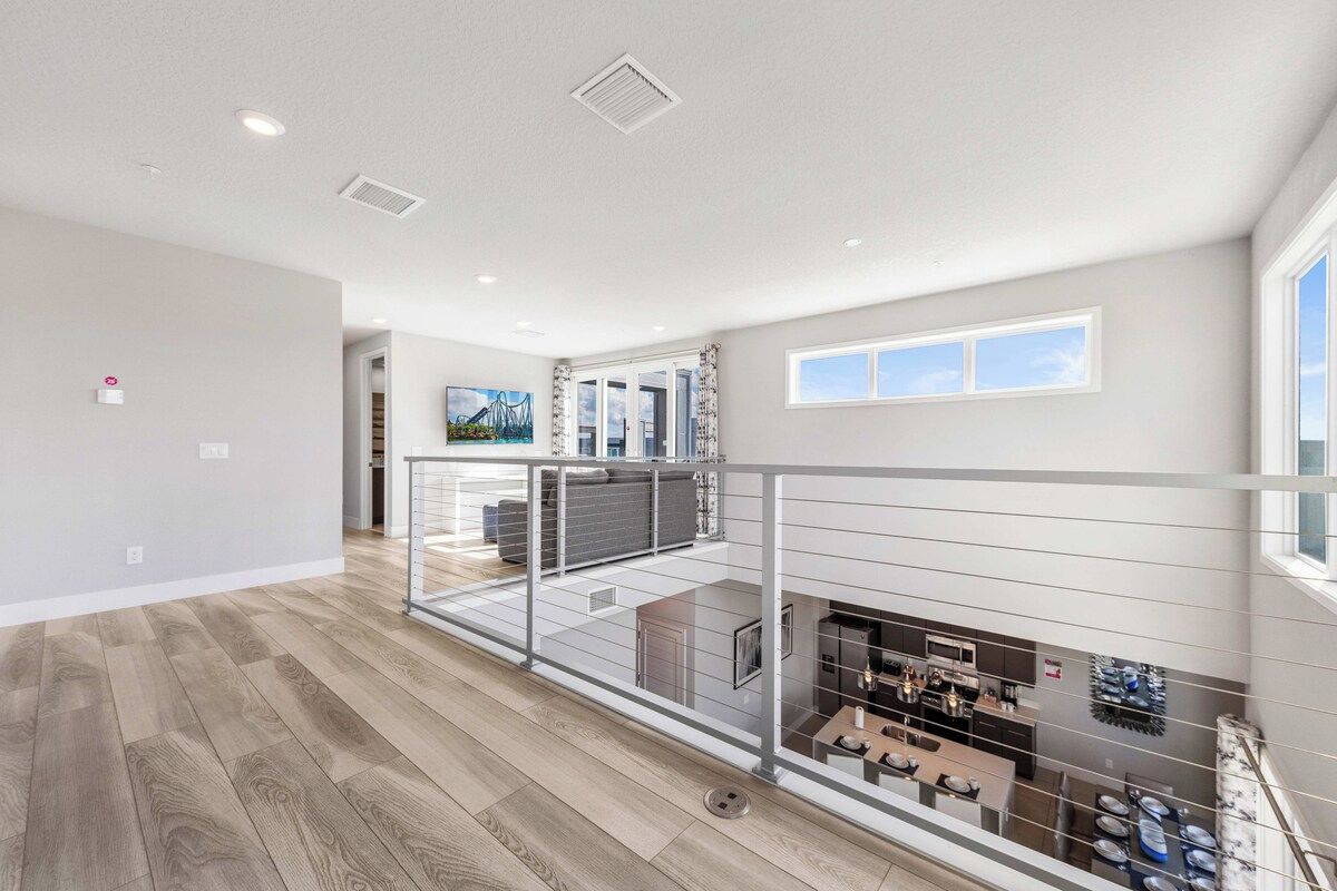 A spacious interior with a balcony overlooking a kitchen area, a dining area, and a living space.