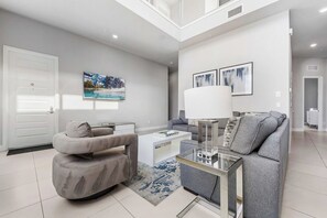 Ein modernes Wohnzimmer mit einem grauen Sofa, einem Couchtisch und einem Bild an der Wand.