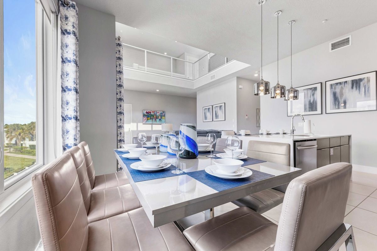 A modern dining area with a glass-top table, cushioned chairs, and a view of the outdoors.