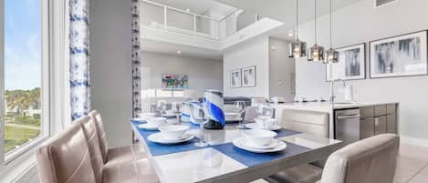 A modern dining area with a glass-top table, cushioned chairs, and a view of the outdoors.