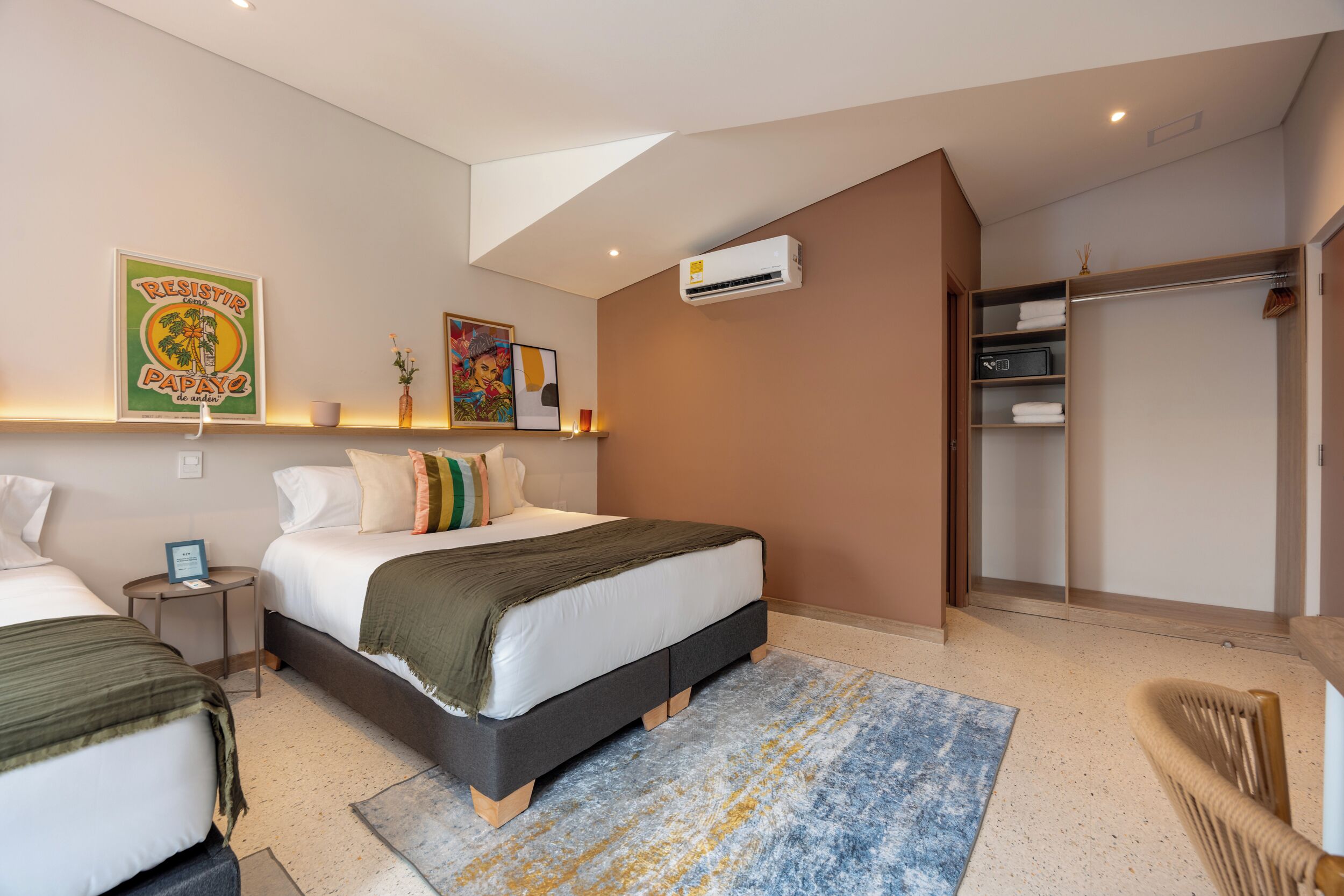 A bedroom with two beds, a large window, an air conditioning unit, and a walk-in closet.