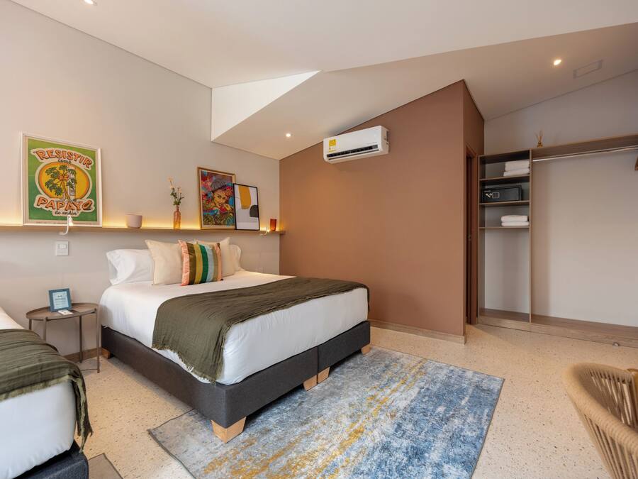 A bedroom with two beds, a large window, an air conditioning unit, and a walk-in closet.