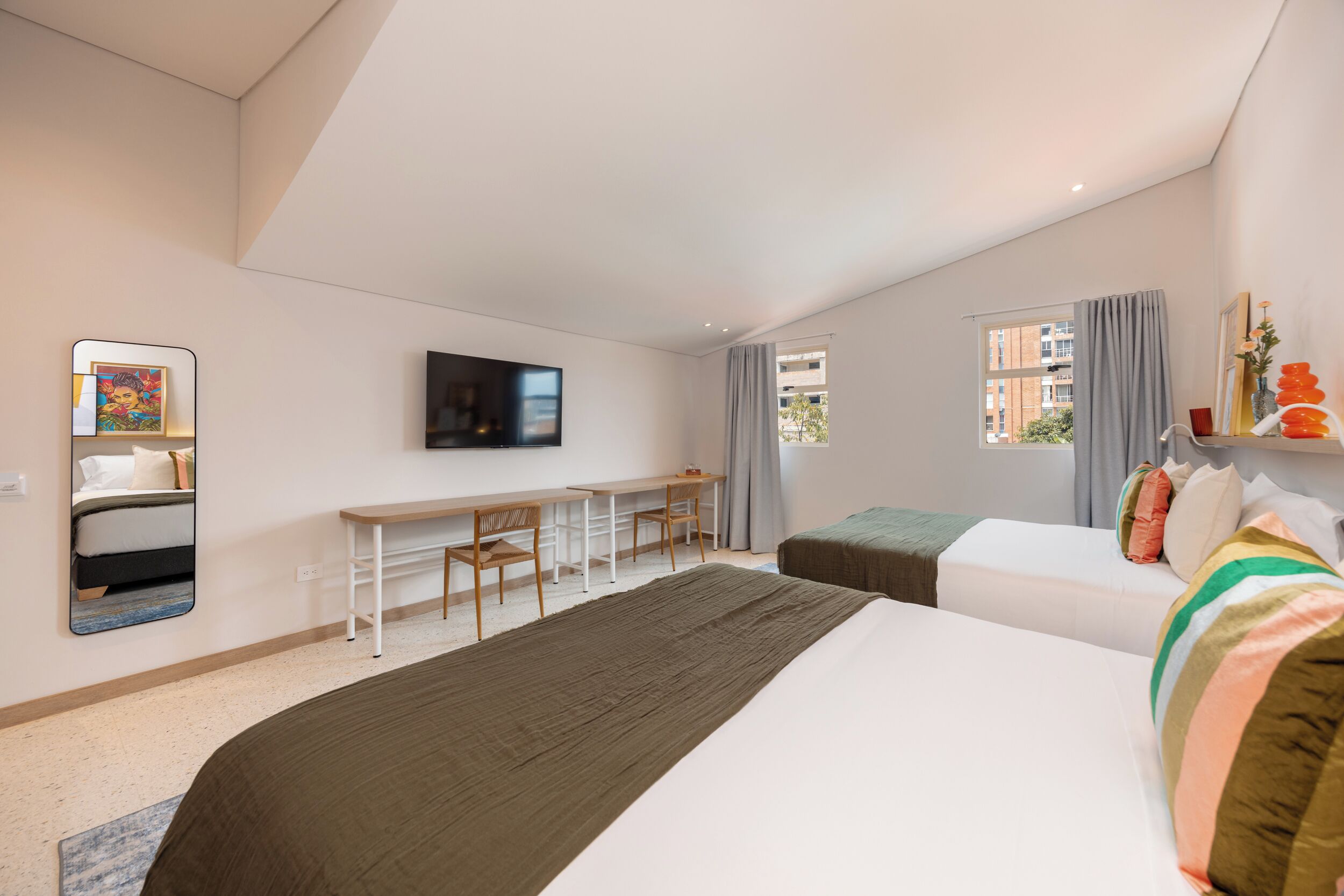 Una habitación de hotel moderna con cama, escritorio, televisor y ventana con cortinas.