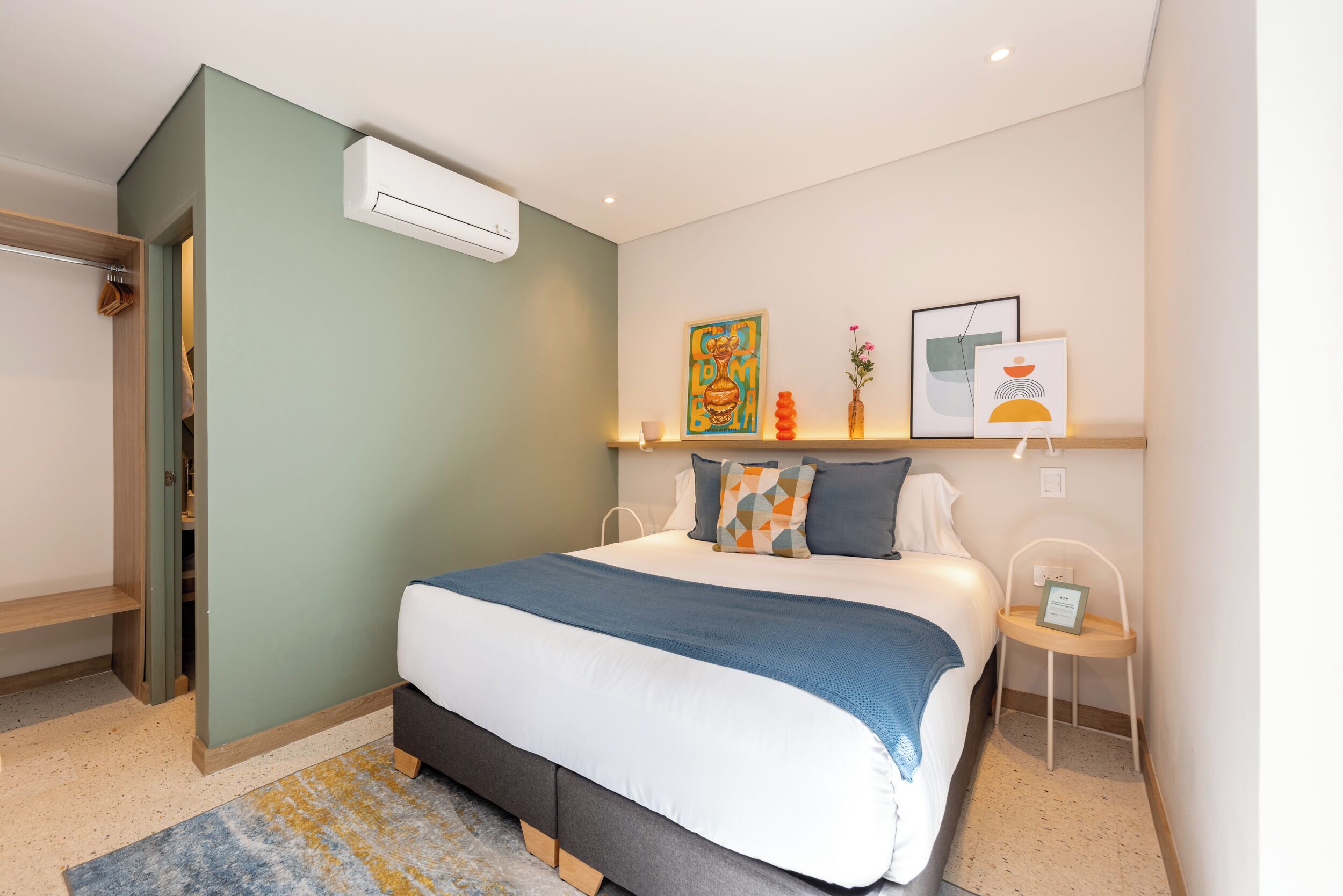 Ein Schlafzimmer mit Bett, Nachttischen, einem Kleiderschrank und einer Klimaanlage.