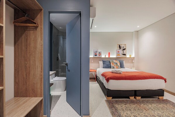 Un dormitorio moderno con cama, mesita de noche y vestidor.