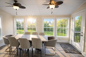 A sunroom with a large table and chairs, two ceiling fans, and large windows offering a view of a green landscape. - Sandy Springs Spacious 3 Bedroom, 2 Bath | 2 King Beds | Central Location (Atlanta)