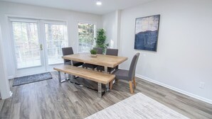 A dining area with a wooden table, four chairs, a bench, and a potted plant. - 7 BR / 5 BA | 2 Homes Sandy Springs Near Buckhead (Atlanta)