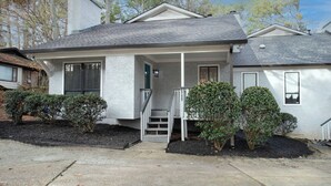 A single-story house with a front porch, a chimney, and a small front yard with shrubs. - 7 BR / 5 BA | 2 Homes Sandy Springs Near Buckhead (Atlanta)