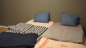 Un lit avec une literie à rayures et unie, deux oreillers et une couverture à motifs.