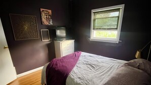 Une chambre à coucher avec un lit, un ventilateur de plafond, une commode et une fenêtre.