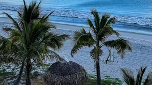 Una spiaggia con palme e una capanna con tetto di paglia.