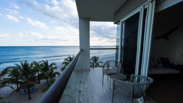 Un balcone con vista sull'oceano, una sedia e un divano.