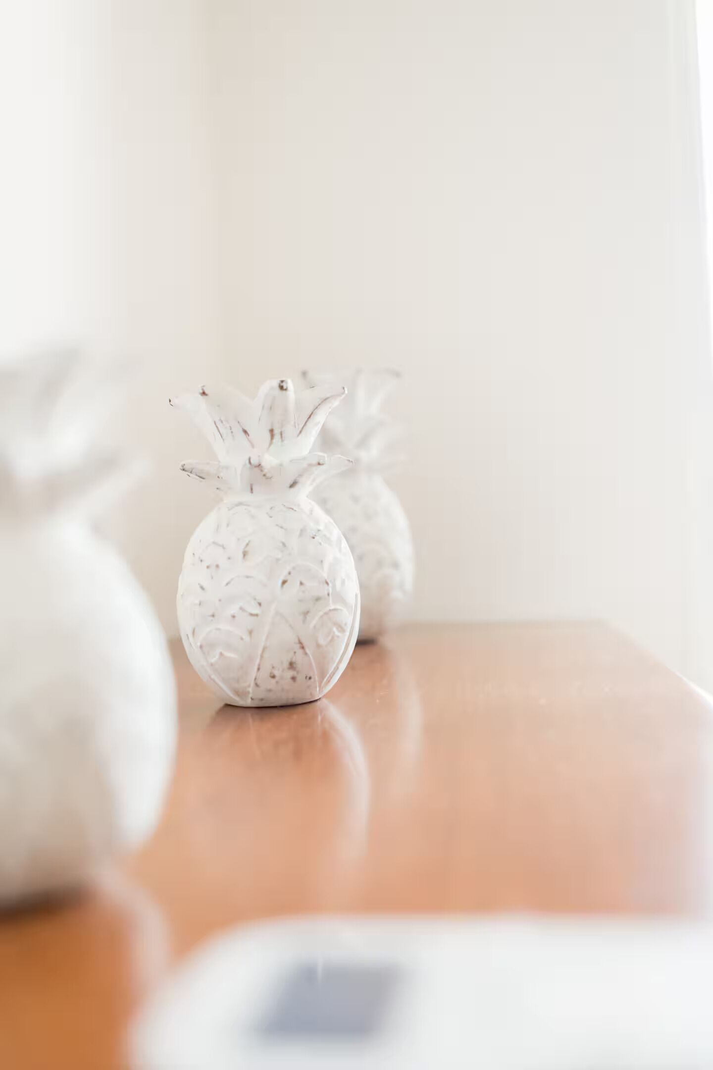 Trois vases blancs en forme d’ananas, posés sur une table en bois.