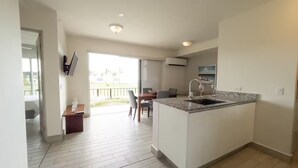 Cozinha moderna com ilha central, área de jantar com mesa e cadeiras, e vista para o exterior através de uma grande porta deslizante.