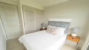 Quarto com cama, mesas de cabeceira, guarda-roupa e cabeceira estampada.
