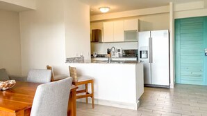 Cozinha moderna com ilha central, armários brancos e porta verde-água.