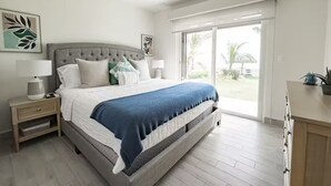 A modern bedroom with a large bed, a ceiling fan, and a view of the outdoors through a sliding glass door. - Seashore Villa Retreat -C6-PBA- 2 bed, 2 bath (Punta Chame)
