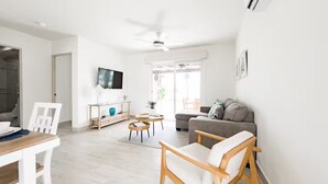 A modern living room with a sofa, a dining table, and a TV. - Seashore Villa Retreat -C6-PBA- 2 bed, 2 bath (Punta Chame)