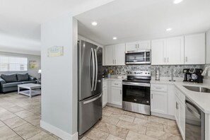 A modern kitchen with stainless steel appliances, white cabinetry, and a tiled backsplash. - Private Villa on Siesta Key, FL (Sarasota)