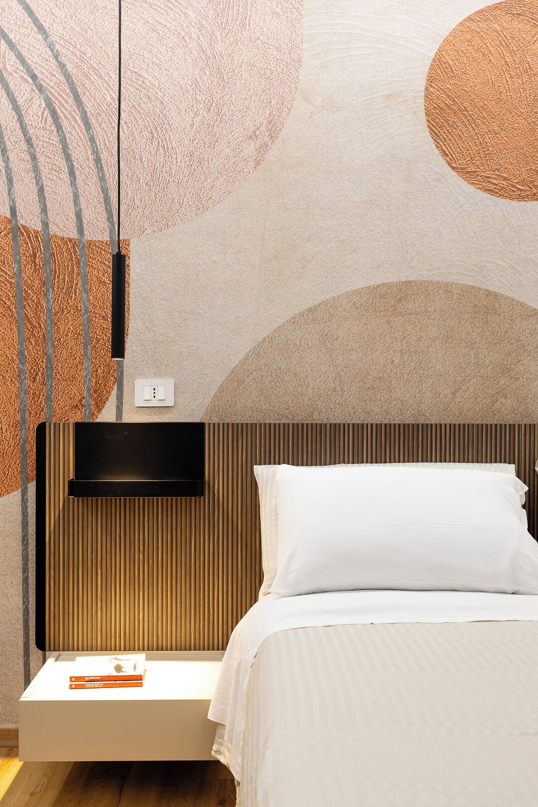 Een moderne slaapkamer met een bed, nachtkastje en een televisie aan de muur.