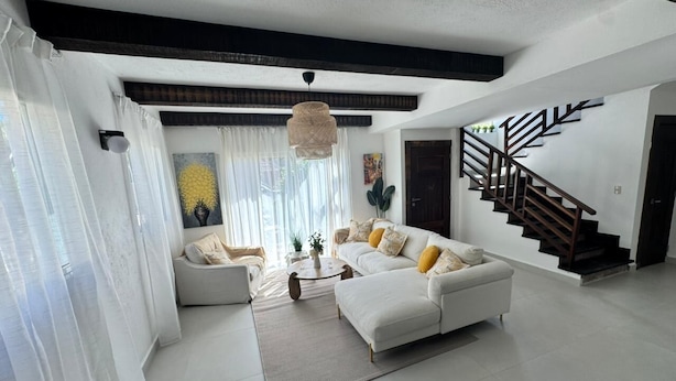 A modern living room with a white sofa, a coffee table, and a staircase. - Villa Postosomar Cabarete (Cabarete)