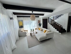 A modern living room with a white sofa, a coffee table, and a staircase. - Villa Postosomar Cabarete (Cabarete)