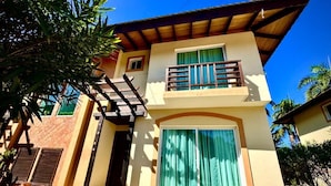 A two-story building with a balcony, a large sliding glass door, and a staircase leading to the upper floor. - Villa Postosomar Cabarete (Cabarete)