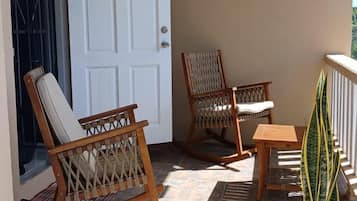 A balcony with two rocking chairs, a small table, and a potted plant.