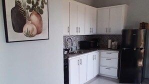 Una cocina moderna con armarios blancos, un refrigerador negro y un salpicadero de azulejos.