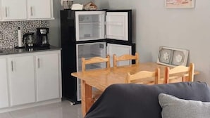 Un espace de vie compact comprenant un coin cuisine, un coin repas et un canapé.