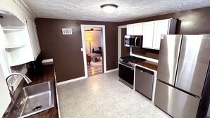 A compact kitchen with stainless steel appliances, a microwave, and a refrigerator. - Cozy 3-bedroom house in Granger, Indiana (Granger)