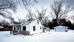 A single-story house with a garage, surrounded by trees and covered in snow. - Cozy 3-bedroom house in Granger, Indiana (Granger)