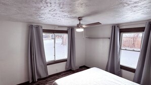 A room with a bed, wooden flooring, a ceiling fan, and windows with curtains. - Cozy 3-bedroom house in Granger, Indiana (Granger)