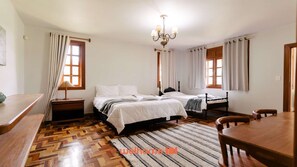 Ein Schlafzimmer mit zwei Betten, Holzboden, einer Kristallleuchter und einem Essbereich mit Tisch und Stühlen.