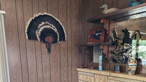 Ein gemütliches Zimmer mit Holzwand, Kamin und einem gemusterten Sessel.