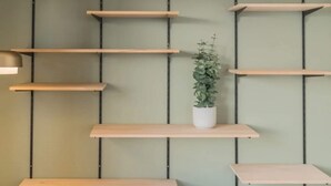 Un mur avec plusieurs étagères en bois et un luminaire suspendu.