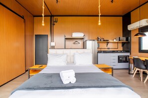 A modern hotel room with a bed, bedside tables, a small kitchenette, and a seating area. - Romantic Cabin Near Florianopolis Vst041 (Anitapolis)