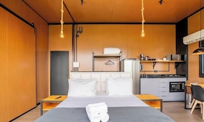 A modern hotel room with a bed, bedside tables, a small kitchenette, and a hanging light fixture. - Romantic Cabin Near Florianopolis Vst041 (Anitapolis)