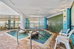 Uma área de piscina com hidromassagem, uma piscina menor e uma escadaria que leva a um andar superior.